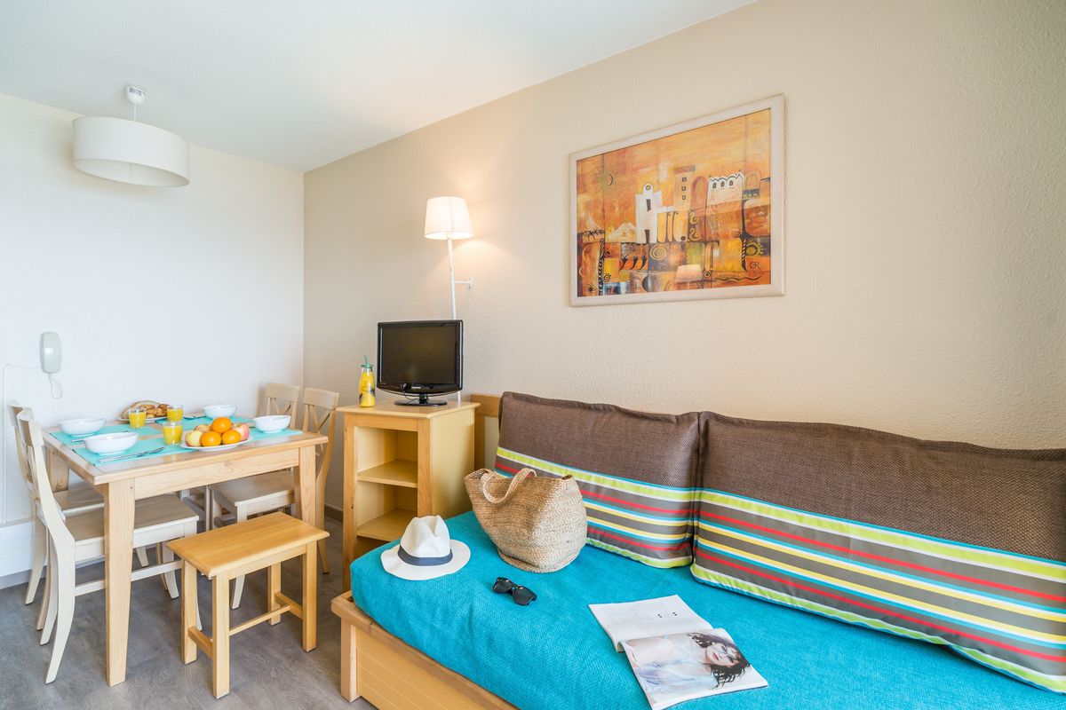 Salon avec 2 canapés-lits, coin repas et balcon vue piscine — Appartement 1 Chambre Cannes