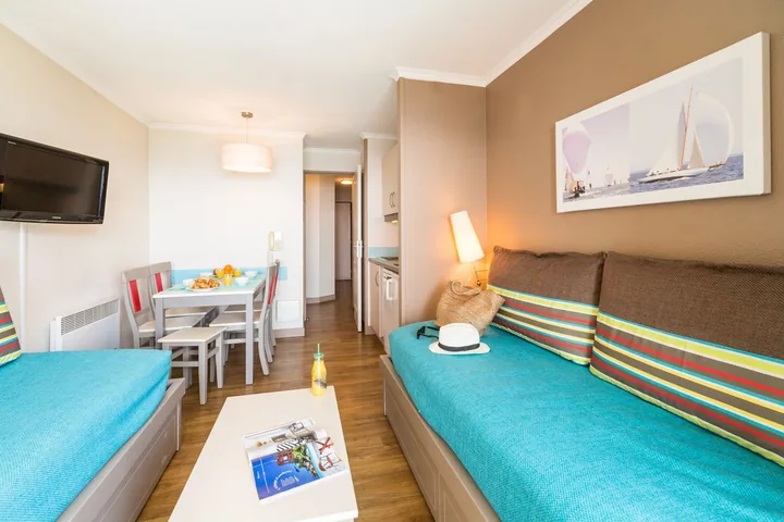 Living room with dining area and sea view in a one-bedroom apartment of the residence